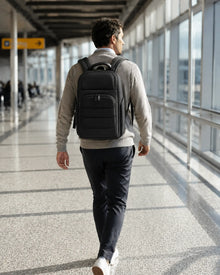 Reisende Person mit dem GlobePro Rucksack in Regular in einem modernen Flughafenkorridor.