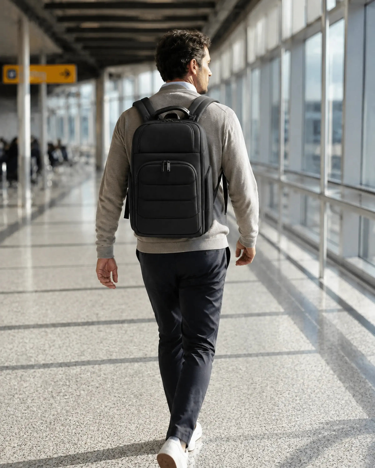 Reisende Person mit dem GlobePro Rucksack in Regular in einem modernen Flughafenkorridor.