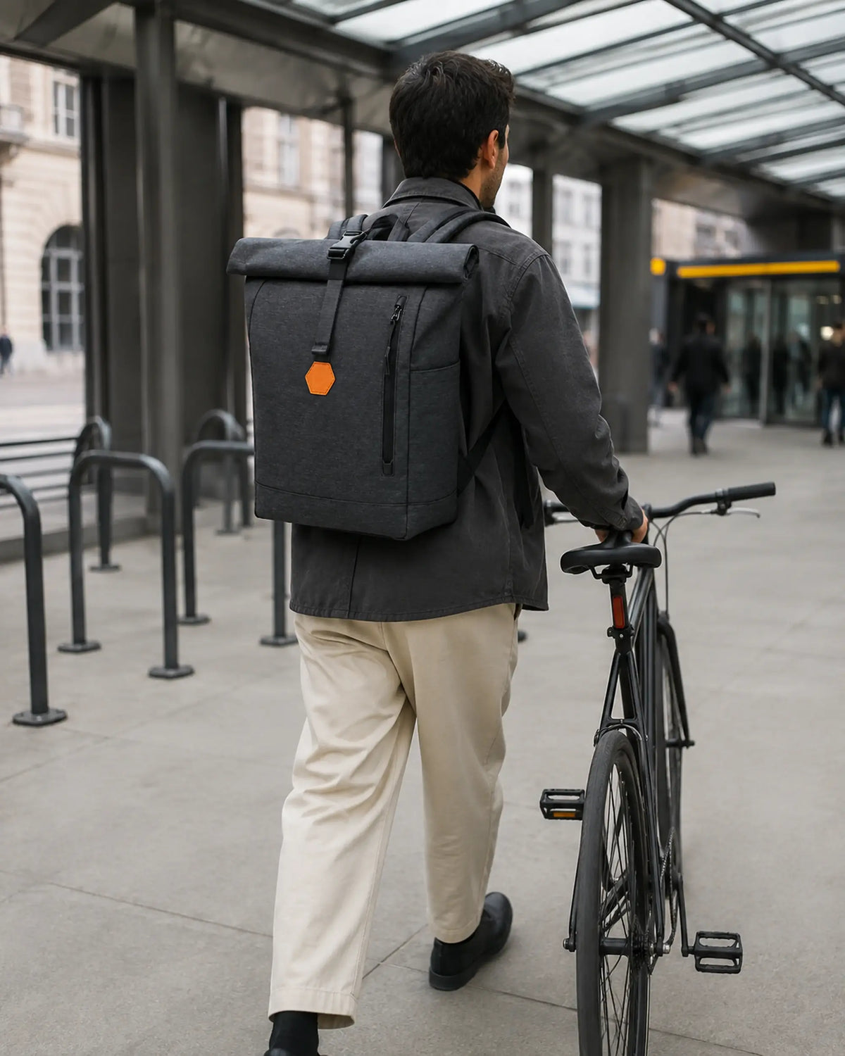 Person mit schwarzem MetroMax Rucksack in Bewegung an einem urbanen Fahrrad-Mobility-Hub.