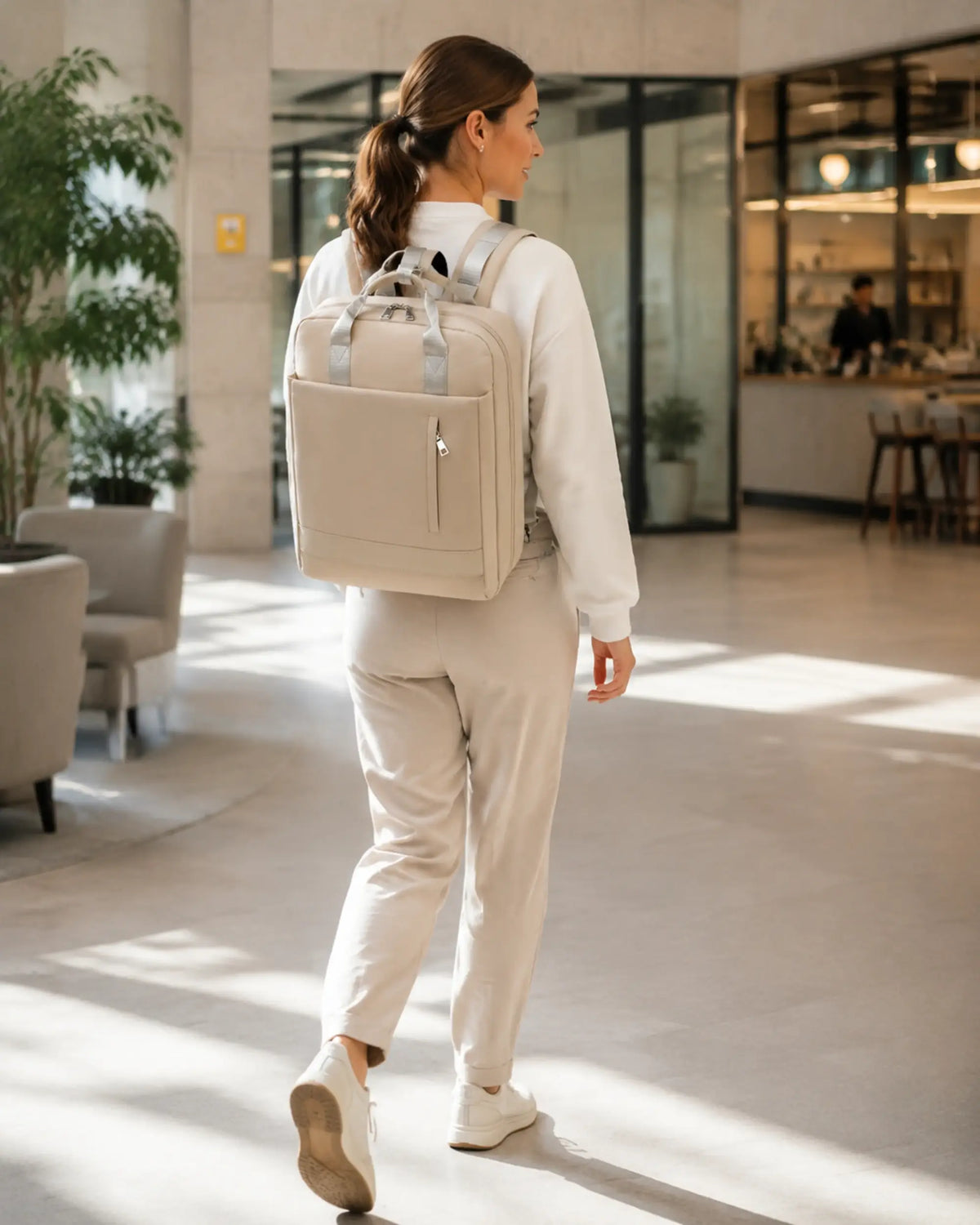 Person mit beigefarbenem CityChic Rucksack in Bewegung in einem modernen Coworking-Bereich.