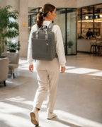 Person mit dunkelgrauem CityChic Rucksack in Bewegung in einem modernen Coworking-Bereich.