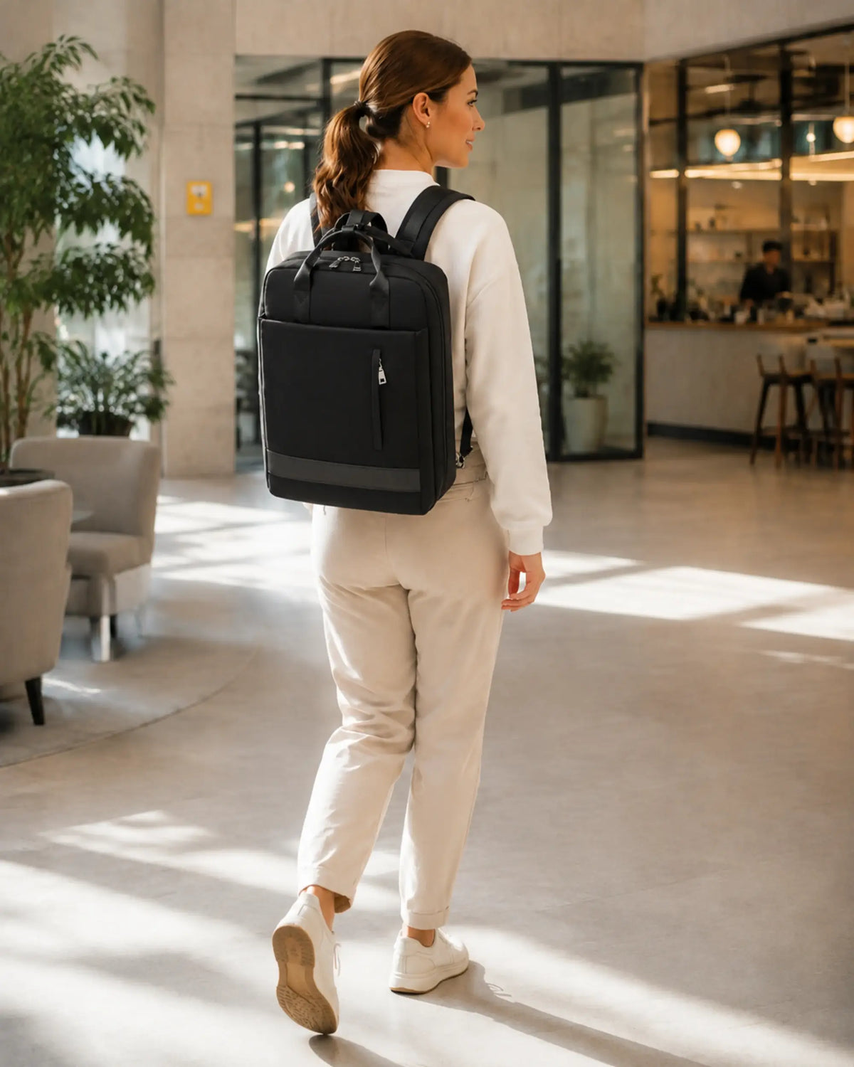 Person mit schwarzem CityChic Rucksack in Bewegung in einem modernen Coworking-Bereich.