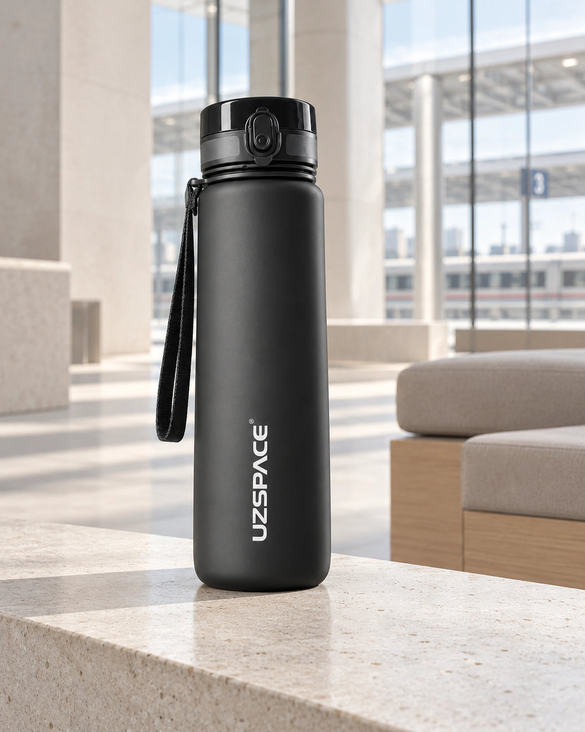 Schwarze CARRYON X HydraGo Trinkflasche auf einer Ablage in einem modernen urbanen Terminal.