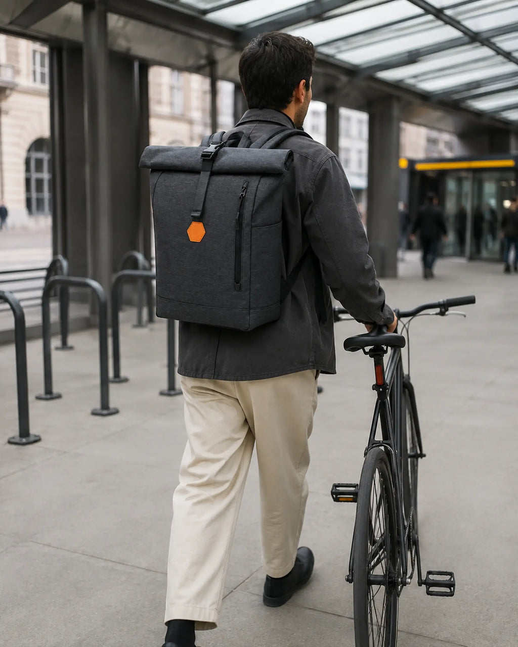 Person mit schwarzem MetroMax Rucksack in Bewegung an einem urbanen Fahrrad-Mobility-Hub.