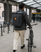 Person mit schwarzem MetroMax Rucksack in Bewegung an einem urbanen Fahrrad-Mobility-Hub.