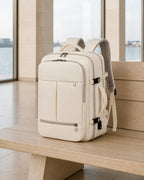 Beiger MetroSlim Reise-Rucksack auf einer Holzbank im modernen Fährterminal.