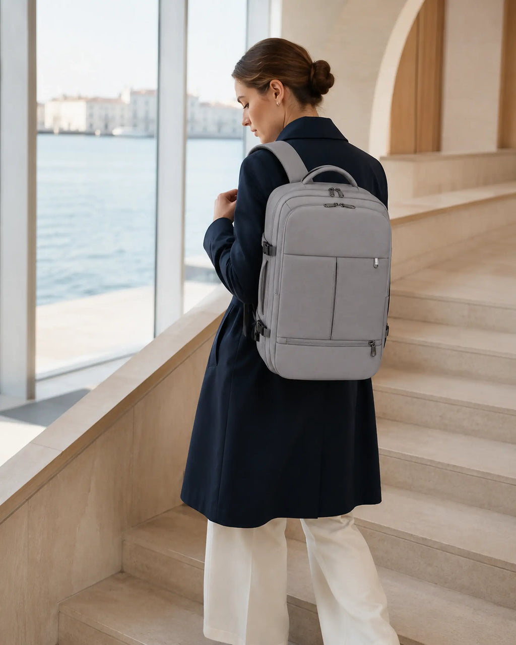 Frau mit grauem MetroSlim Reise-Rucksack auf einer Treppe im Fährterminal.
