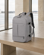 Grauer MetroSlim Reise-Rucksack auf einer Holzbank im modernen Fährterminal.