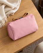 CARRYON X PocketGo Kosmetiktasche in Pink, liegend auf einem Packtisch aus Holz.