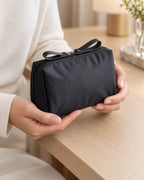 CARRYON X PocketGo Kosmetiktasche in Schwarz, in zwei Händen über dem Packtisch.