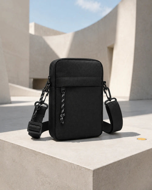 Schwarze UrbanEase Crossbody-Tasche auf einem Podest in einem modernen Museumshof.